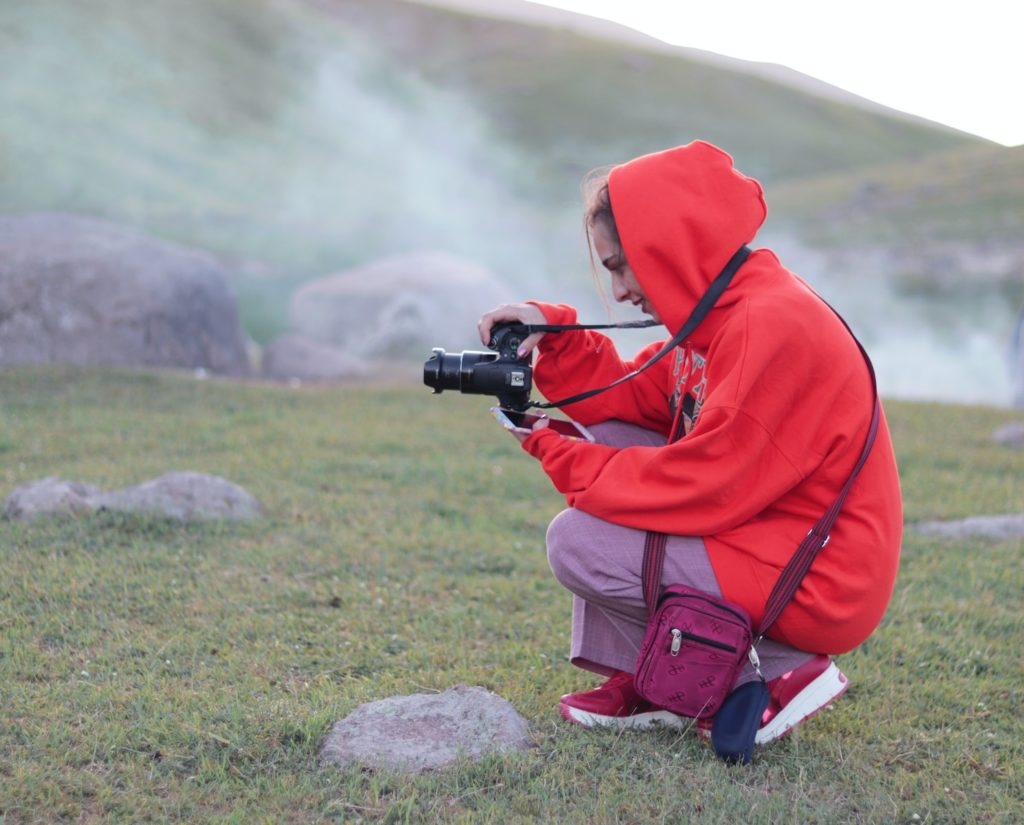 man in red hoodie holding black dslr camera Joilcan Tripod